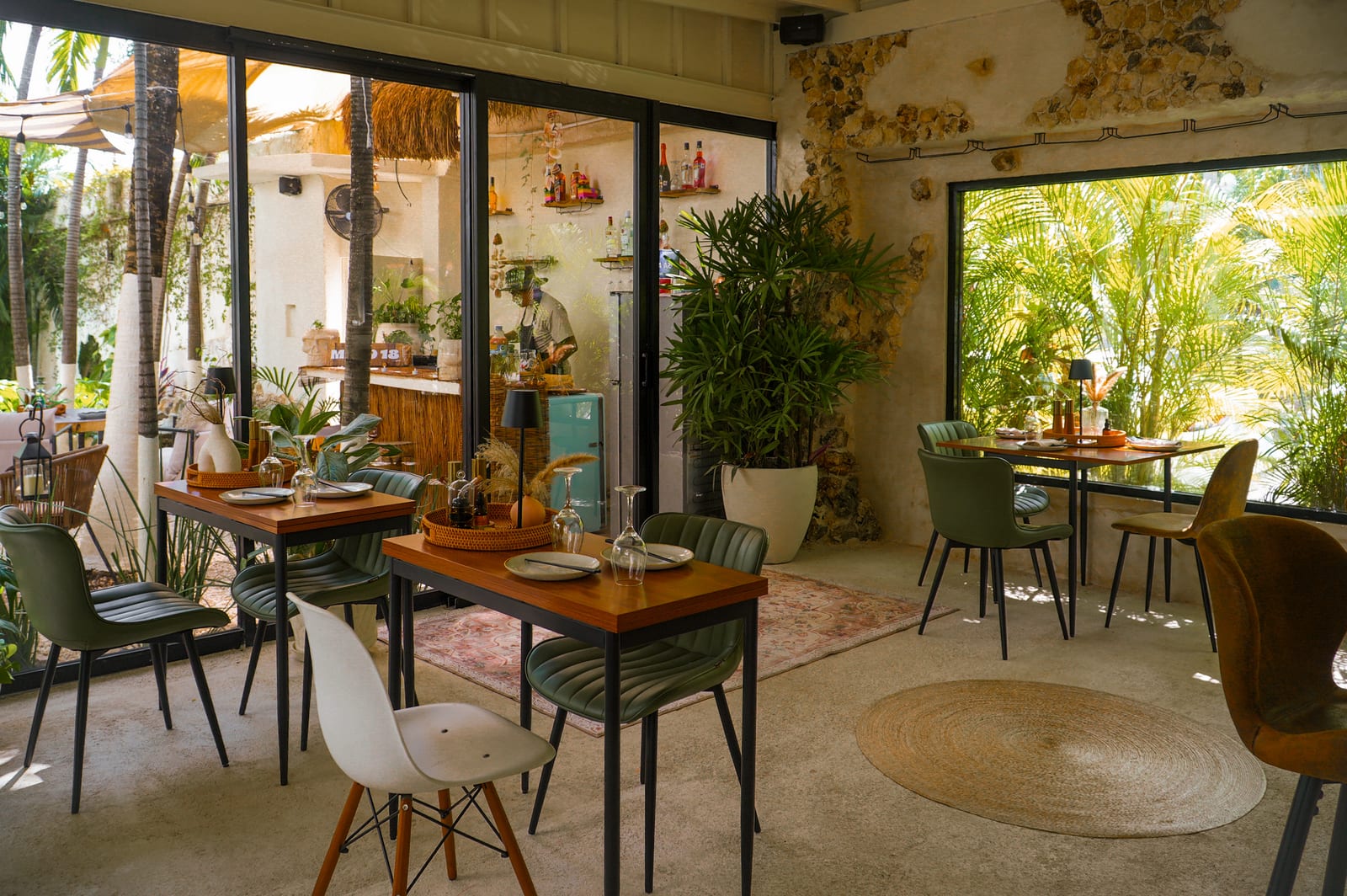 Comedor entre plantas con grandes ventanales al jardín tropical