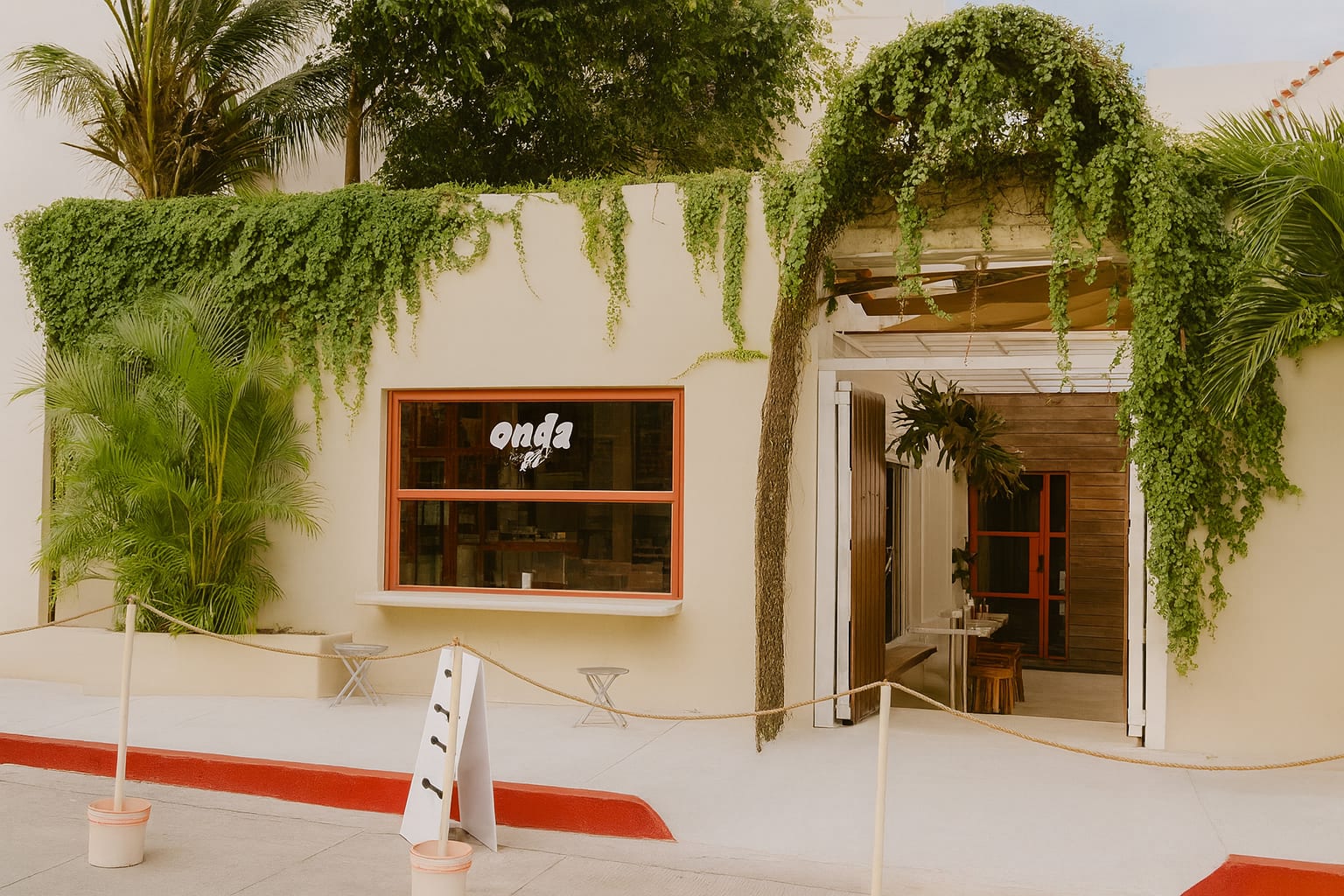 Fachada de Onda Café con su logo entre enredaderas, en el Centro de Cancún